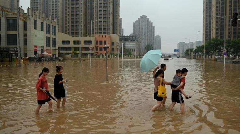 La gente camina por una calle inundada luego de las fuertes lluvias que causaron inundaciones. | AFP