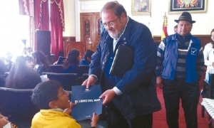Roberto aguilar, ministro de Educación entregando El Libro del Mar a un estudiante. Foto: Internet	