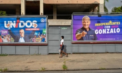Una mujer con tapabocas es vista mientras camina cerca a vallas publicitarias de los candidatos presidenciales Luis Abinader y Gonzalo Castillo | EFE