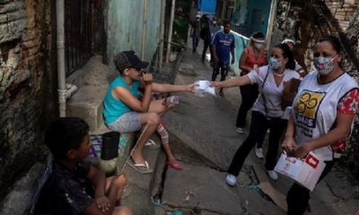 Voluntarios distribuyen mascarillas caseras y alcohol en gel para los moradores de la favela Heliópolis, en Sao Paulo (Brasil). | Fuente: EFE