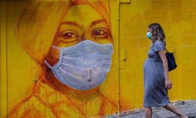 Una mujer embarazada con una máscara facial, como medida de precaución, pasa frente a un mural en una calle de Hong Kong. | Fuente: AFP