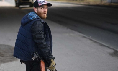 Un Voluntario, con un rifle, protege una carretera principal que conduce a Kiev.