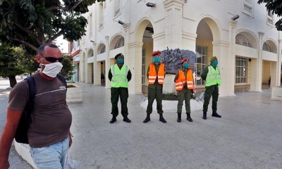 Un hombre pasa delante de agentes policiales que controlan la cuarentena, en La Habana. | EFE
