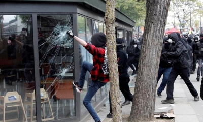 Jóvenes rompen el escaparate de un establecimiento durante una marcha por el Día Internacional de los Trabajadores, en París. Foto: EFE