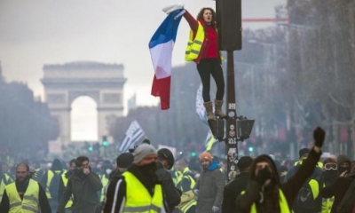 Una mujer grita consignas subida a un semáforo durante una protesta en los Campos Elíseos en París (Francia). | Foto archivo | EFE