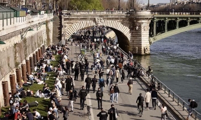 Decenas de personas caminan por la ribera del Sena, en París. 
