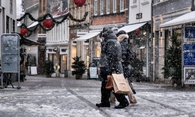 Los peatones caminan por una calle cubierta de nieve durante la caída de nieve en Aalborg (Dinamarca)