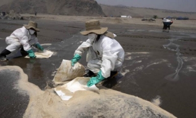Cuadrillas de limpieza trabajan para remover petróleo de la playa Cavero en Callao, Perú.