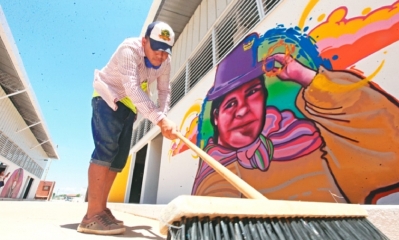 Un obrero limpia un pasillo, cerca de uno de los más de 100 murales que embellecen la fachada del nuevo mercado La Ramada, en el D-10