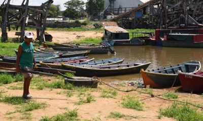 Un pescador camina entre botes encallados por la reducción del nivel del río Paraguay. Foto: AFP.