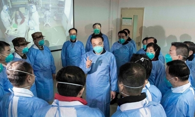 El primer ministro chino, Li Keqiang, con una máscara y un traje protector, habla con los trabajadores médicos mientras visita el hospital Jinyintan