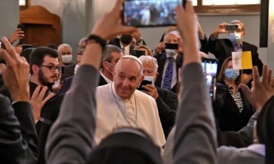 La gente toma fotos con sus teléfonos móviles del Papa Francisco cuando ingresa a la catedral maronita