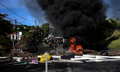 Un bloqueo con ramas de árboles, material de construcción y un pequeño incendio.