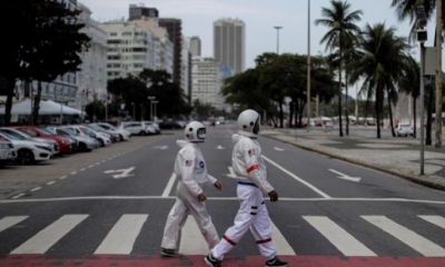 El contador brasileño Tercio Galdino, de 66 años, y su esposa, Alicea Galdino, caminan por la playa de Leme con trajes protectores