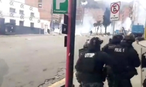 De fondo, una humareda de gas lacrimògeno que fue lanzada por la Policía