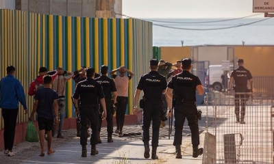 Efectivos de la Policía Nacional trasladan a un grupo de inmigrantes en Ceuta. | EFE