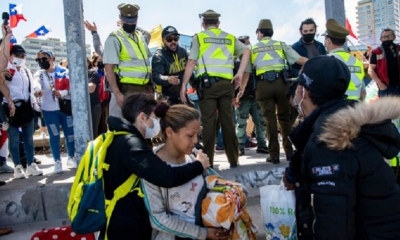Los migrantes venezolanos son asediados por manifestantes durante una marcha de protesta contra la migración ilegal en Iquique, Chile.