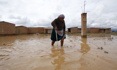 Una mujer camina en medio del agua en las inundaciones en Cliza. 