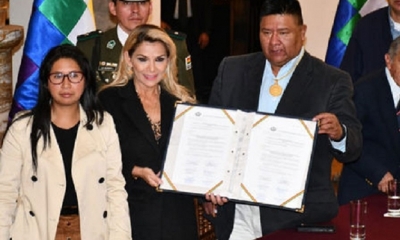 Jeanine Áñez sostiene, junto al presidente de Diputados Sergio Choque, la ley promulgada. Aparece a la izquierda la presidenta del Senado, Eva Copa.