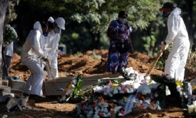 Empleados cargan un ataúd de una persona supuestamente de COVID-19 durante su funeral en el cementerio de Vila Formosa en Sao Paulo (Brasil).