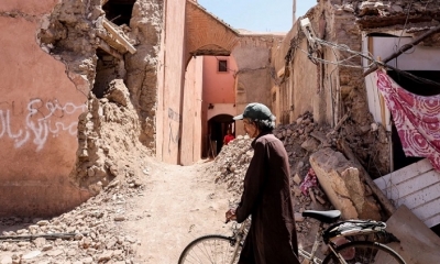 Un hombre camina con su bicicleta por una calle con edificios dañados que se derrumbaron en un terremoto en Marrakech, Marruecos