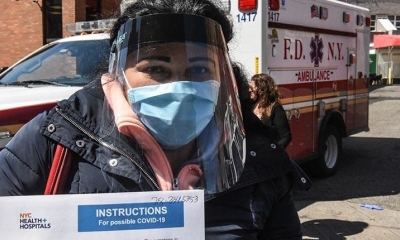 Una mujer muestra el test para detectar Covid-19 en las puertas de un hospital en Nueva York. | AFP