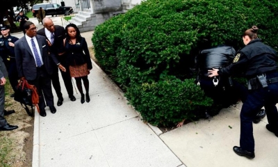 Bill Cosby, al centro, mira a una manifestante que fue detenida en los matorrales/Foto. RRSS