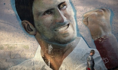 Un hombre pasa junto a un mural que representa al tenista serbio Novak Djokovic.