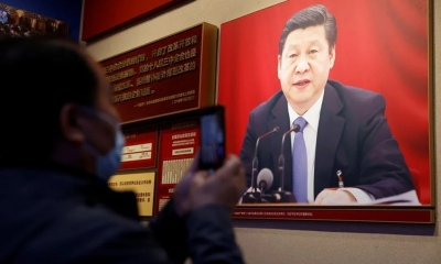 Un hombre sostiene un teléfono móvil frente a una imagen del presidente chino Xi Jinping expuesta en el Museo del Partido Comunista de China en Beijin