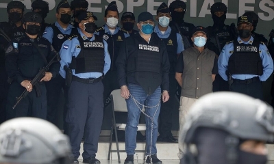 El expresidente de Honduras Juan Orlando Hernández rodeado de policías y esposado tras su detención este martes.