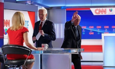 Joe Biden habla con la presentadora de noticias de CNN cuando Bernie Sanders abandona el escenario después de que ambos participaran en el 11º debate 
