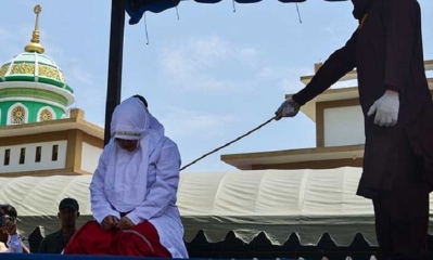 Un miembro de la policía religiosa de la ley islámica azota públicamente a una mujer en la ciudad de Banda Aceh/Foto. RRSS
