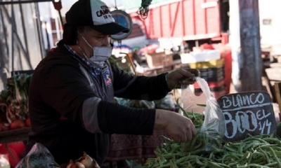 Un trabajador de una feria libre pone verduras en bolsas plásticas en la comuna de Peñalolén, en Santiago (Chile). | Fuente: EFE