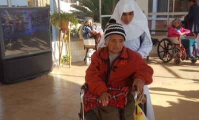 Una religiosa traslada a una anciana en el Hogar San Ramón. Foto: ANF