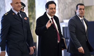 El primer ministro libanés Hassan Diab (centro) saluda tras anunciar su dimisión. | EFE
