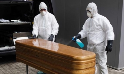Trabajadores de una funeraria sacan un ataúd para proceder a su desinfección antes de trasladarlo al cementerio.