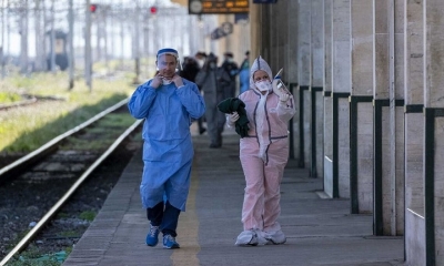 Personal de una estación de trenes de Italia con trajes especiales para protegerse el coronavirus. EFE