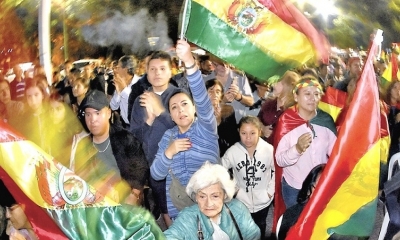 Concurrentes al cabildo flamean banderas de Bolivia. 