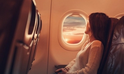 Mujer mirando a través de la ventana del avión (martin-dm / Getty Images)