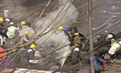 Manifestantes se protegen del gas y los proyectiles en Rangún.