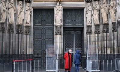 Una persona conversa con un sacerdote en la Catedral de Colonia