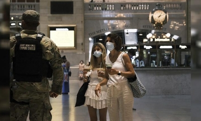 Dos personas usan máscaras mientras caminan en una estación de tren. | AFP