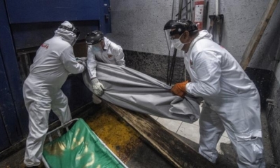 Empleados de la maniobra del panteón Iztapalapa para colocar una bolsa con los restos de una víctima de Covid-19 en un horno en el crematorio