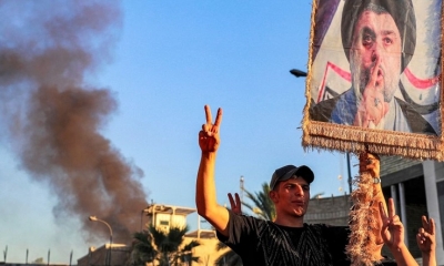 Los partidarios del clérigo chiíta iraquí Moqtada al-Sadr levantan su retrato durante el incendio de la embajada sueca en Bagdad. | Fuente: AFP