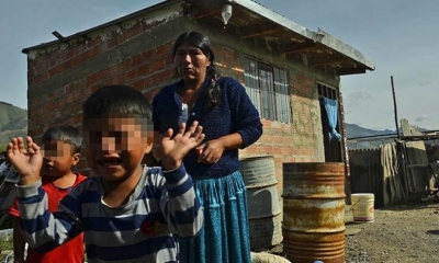 Los gemelos junto a su madre, al fondo la vivienda que fue construida de forma ilegal