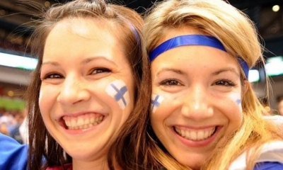 Mujeres jóvenes sonríen con  la bandera de Finlandia en el rostro 