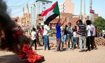 Manifestantes sudaneses levantan banderas nacionales y queman neumáticos en una calle de la capital, Jartum. | AFP