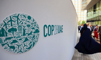 La gente pasa junto a un cartel de la COP28 en la Expo City durante la cumbre climática