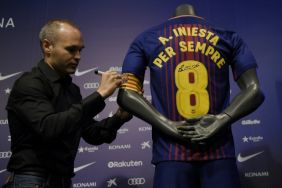 Andrés Iniesta firma su número y el brazalete de capitán en una camiseta conmemorativa de su contrato vitalicio. Foto: AFP