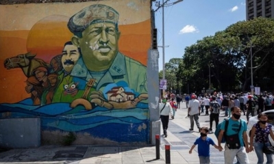 Ciudadanos caminan cerca a un mural con las imágenes de Hugo Chávez y Nicolás Maduro en Caracas (Venezuela). | Fuente: EFE | Fotógrafo: RAYNER PEс R